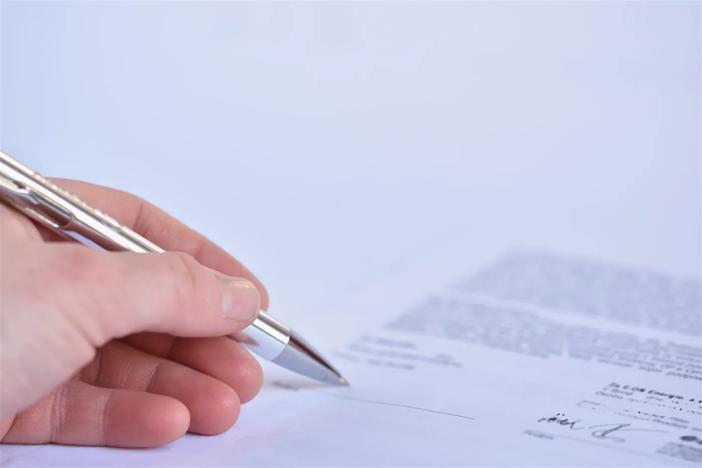 Hand signing a document with a pen